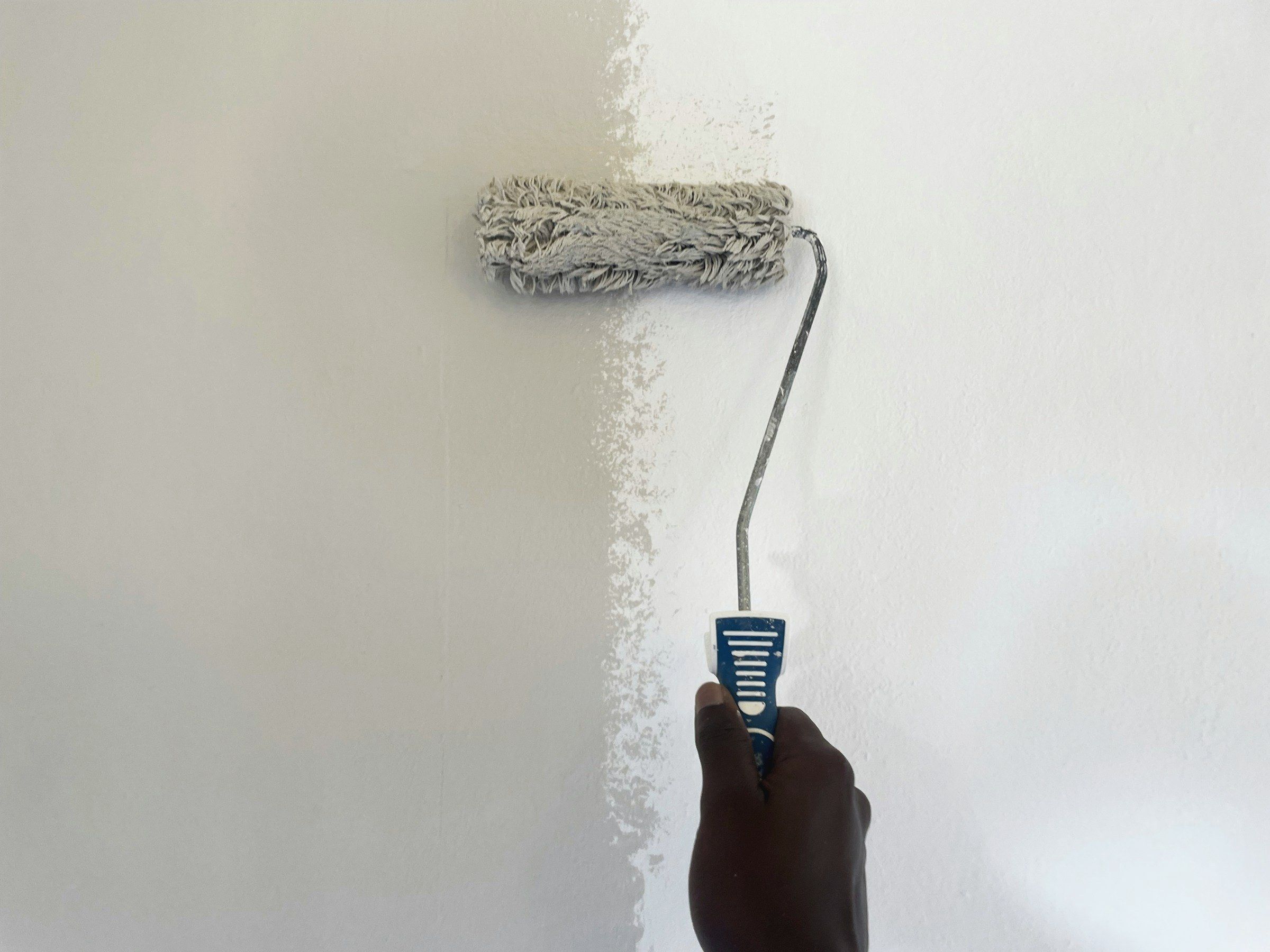 Paint roller applying a fresh coat to a white wall